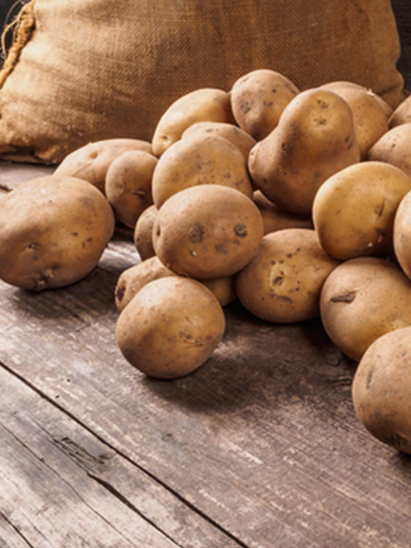 A pile of potatoes with a sack in the background