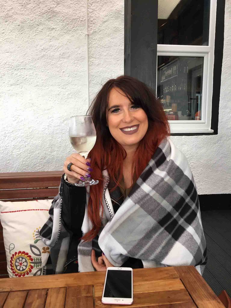 Lady with a glass of wine and blanket around her in the outdoor dining area 'The Terrace' at Peatzeria restaurant on Islay