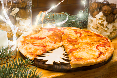 A pizza with a slice as a Christmas tree