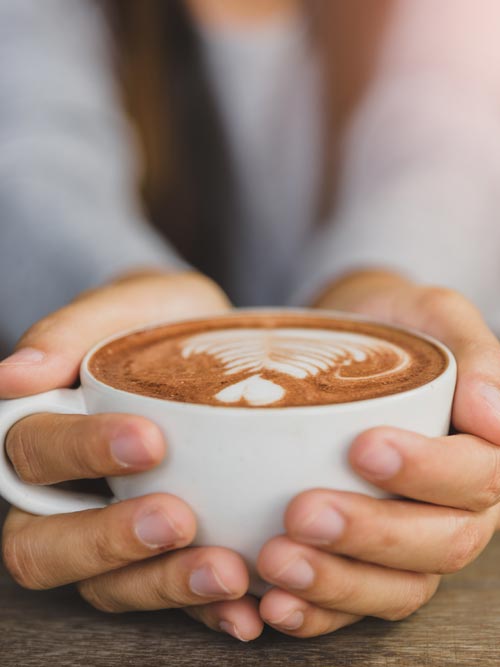 Close up of two hands holding a cup of coffee