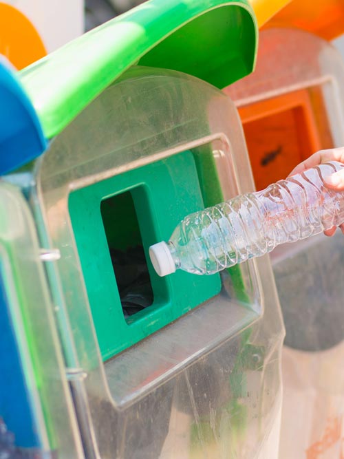 Plastic bottle being placed in a recycling bin