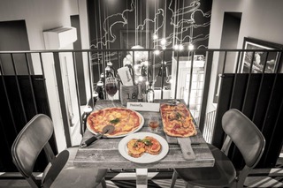 Black and white picture of a table on the balcony at Peatzeria with the food in colour.