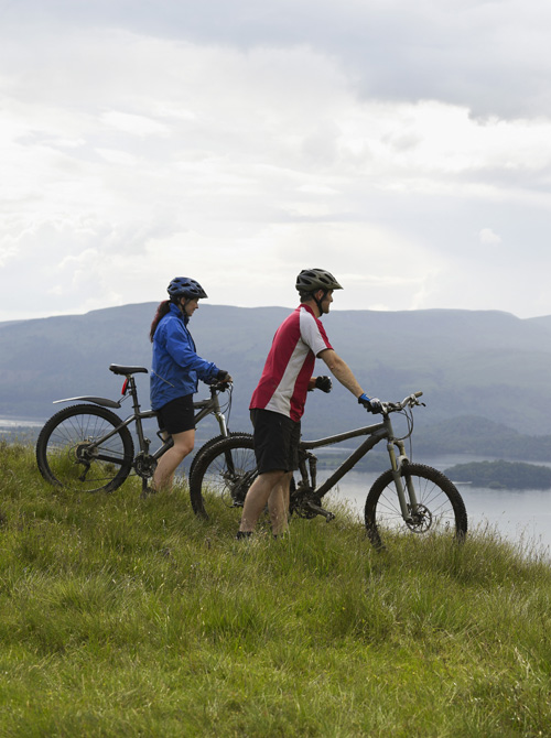 Side view of a couple with bicycles near the peaceful loch