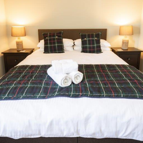 Bed with tartan throw and cushions