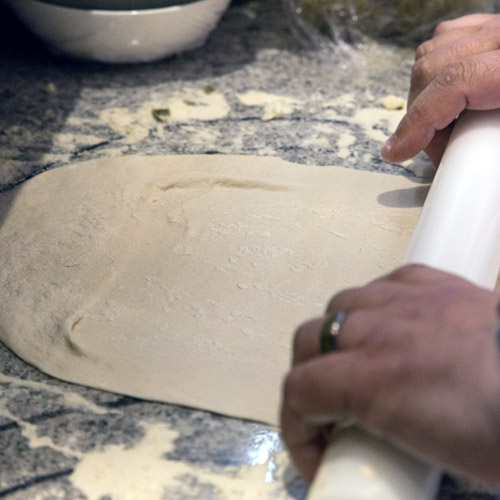 Rolling out pizza base dough with a rolling pin