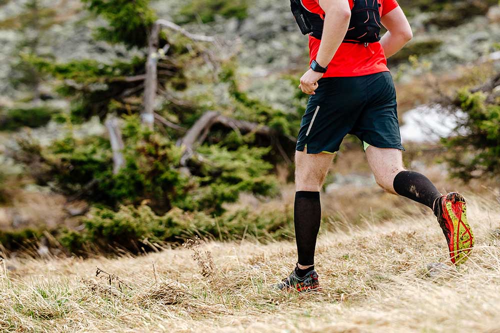 A man in shorts and red top running a fell race.