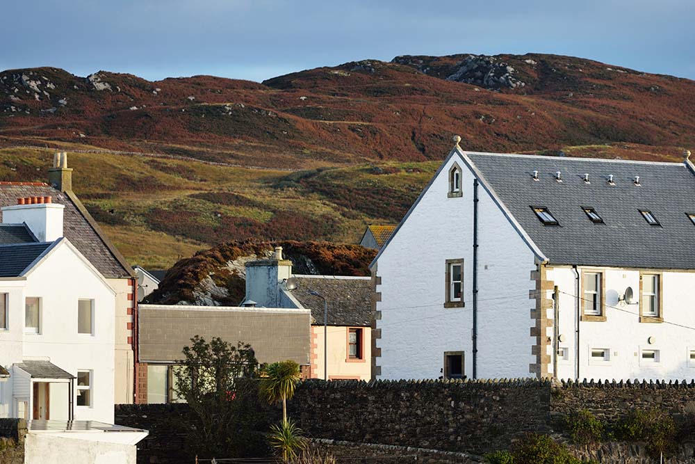 A hill on Islay behind white buildings