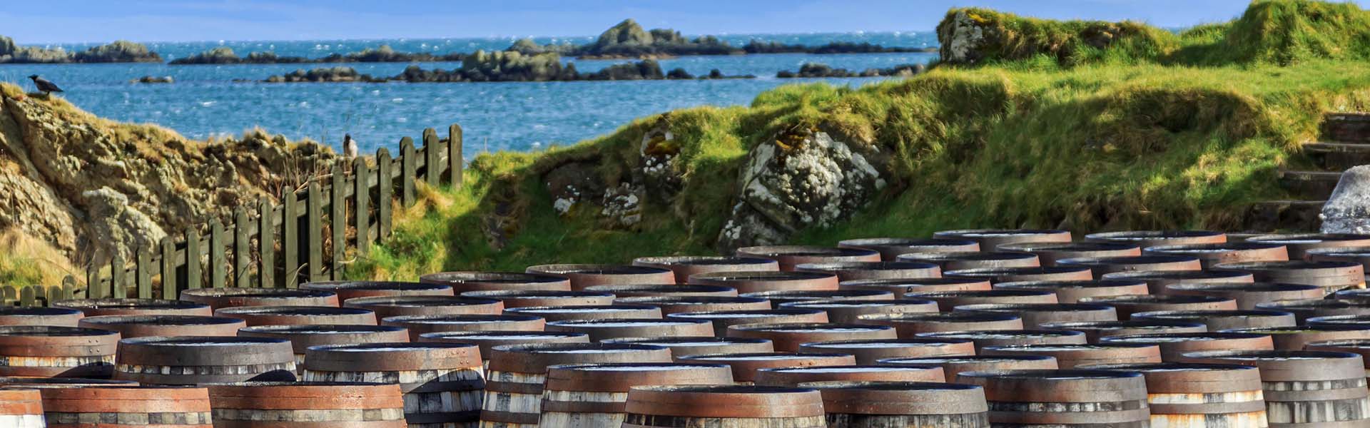 whisky barrels lined up by the water on Islay