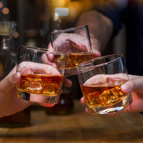 Three whisky drinkers cheering glasses together