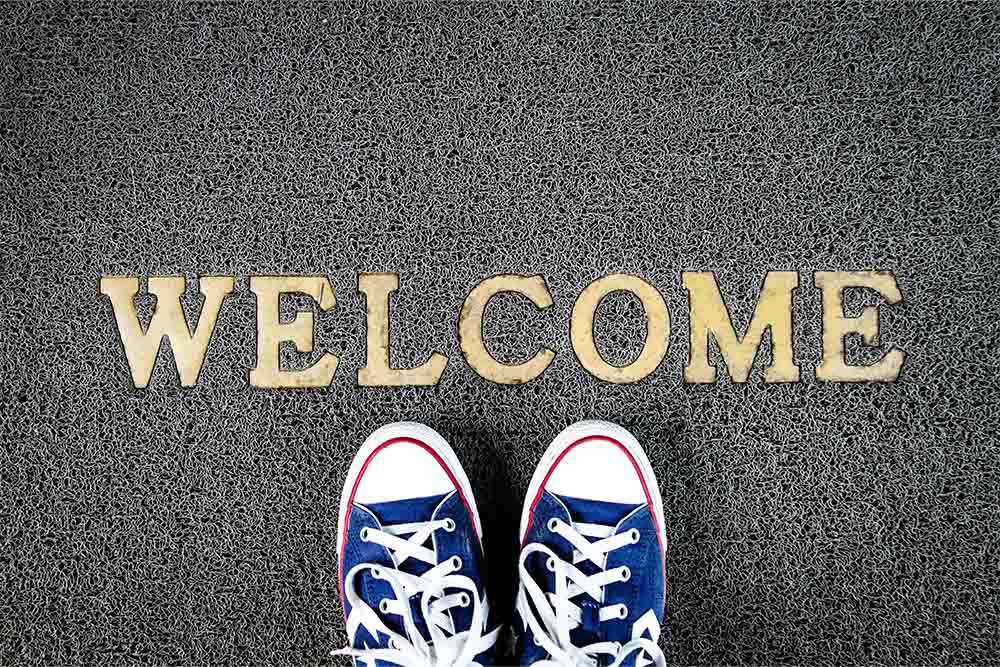 A pair of blue shoes on a 'welcome' mat.