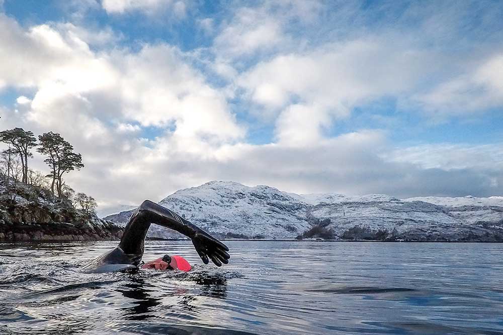 A person swimming in a cold Scottish loch in winter.