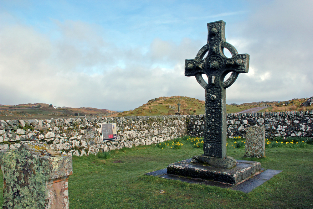 Celtic Cross surrounded by grass and stone walls